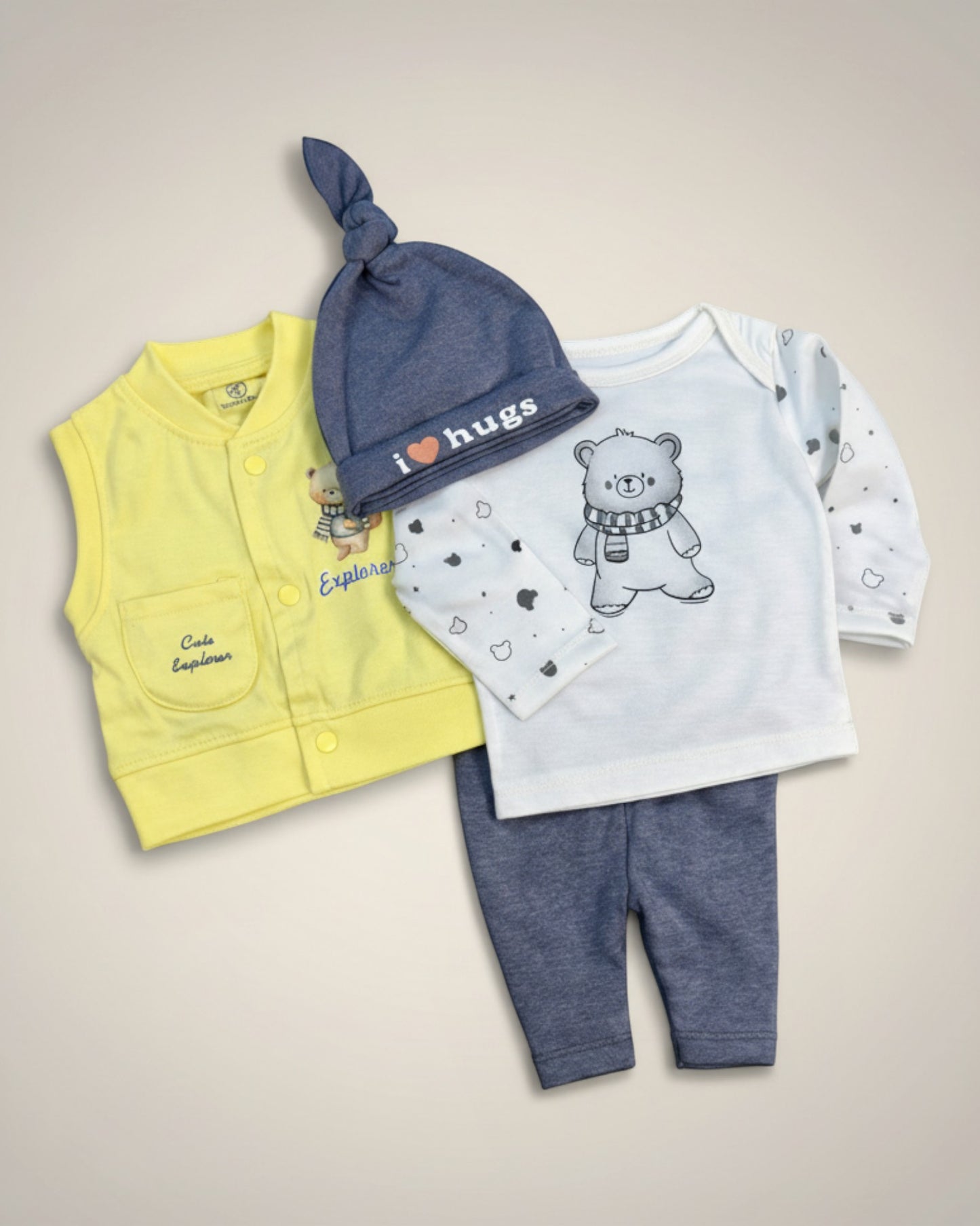 Little Roots newborn 4-piece set: yellow sleeveless vest, blue knotted cap with 'I ❤️ Hugs', white bear print t-shirt, and blue trousers. Cotton blend.