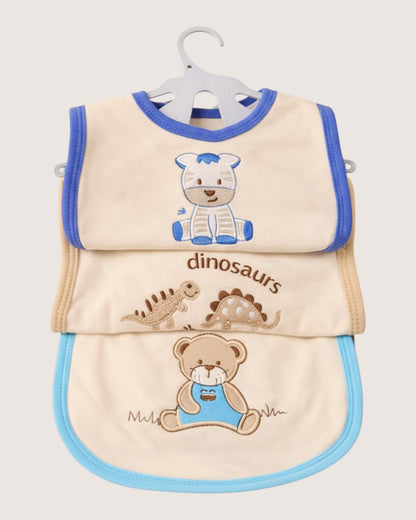 Little Roots pack of 3 cream cotton baby bibs with blue trim, featuring embroidered zebra, dinosaurs, and teddy bear designs.