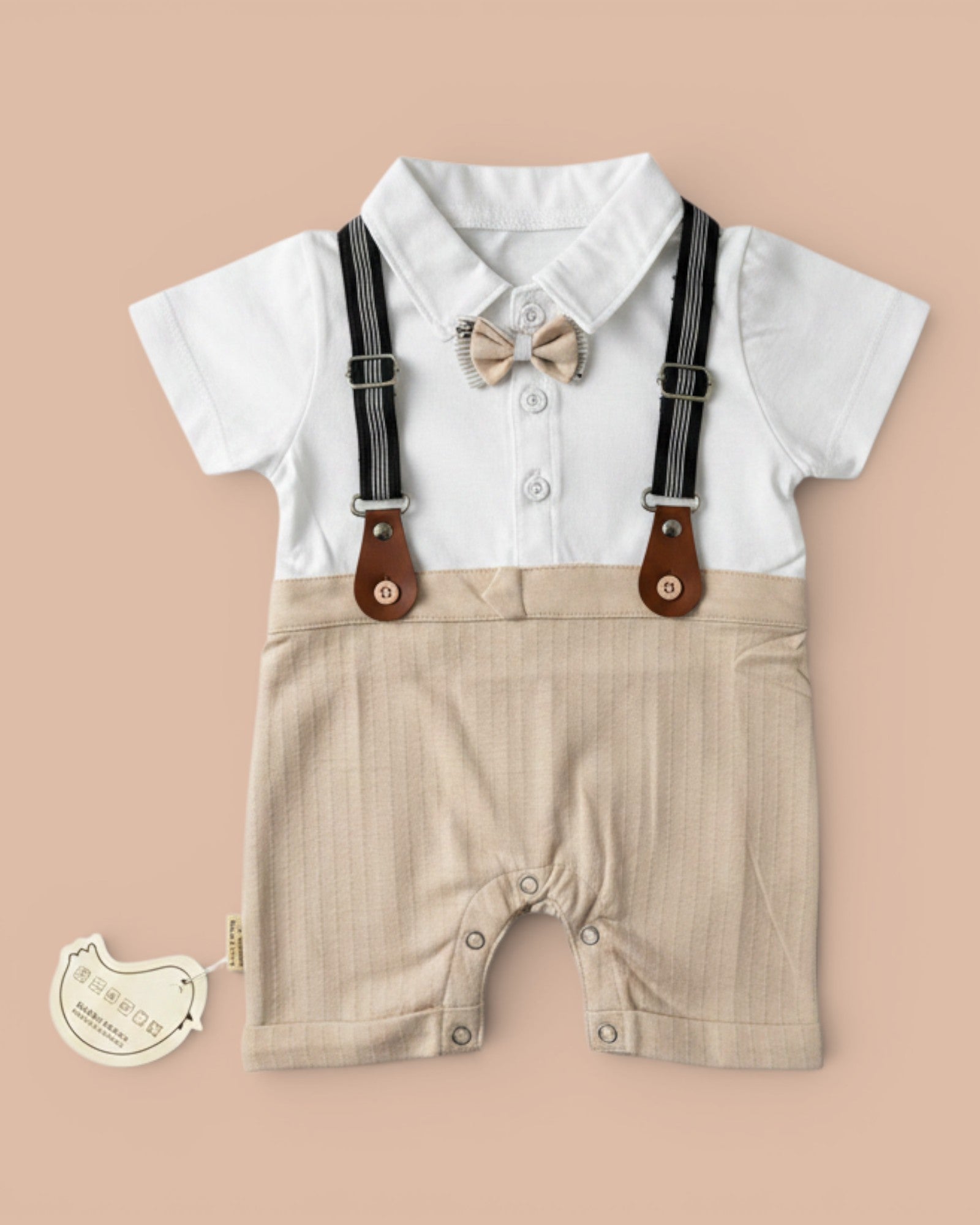 Little Roots baby boy formal romper in white and beige with attached bow tie and suspenders. Soft, breathable fabric with snap buttons.