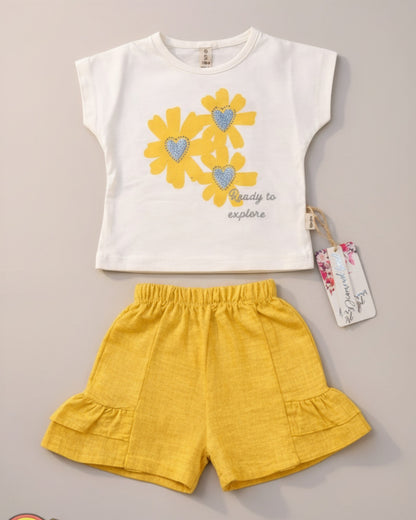 Little Roots Pakistan cream t-shirt with yellow floral print and glitter hearts, paired with yellow ruffle shorts. "Ready to explore" text.