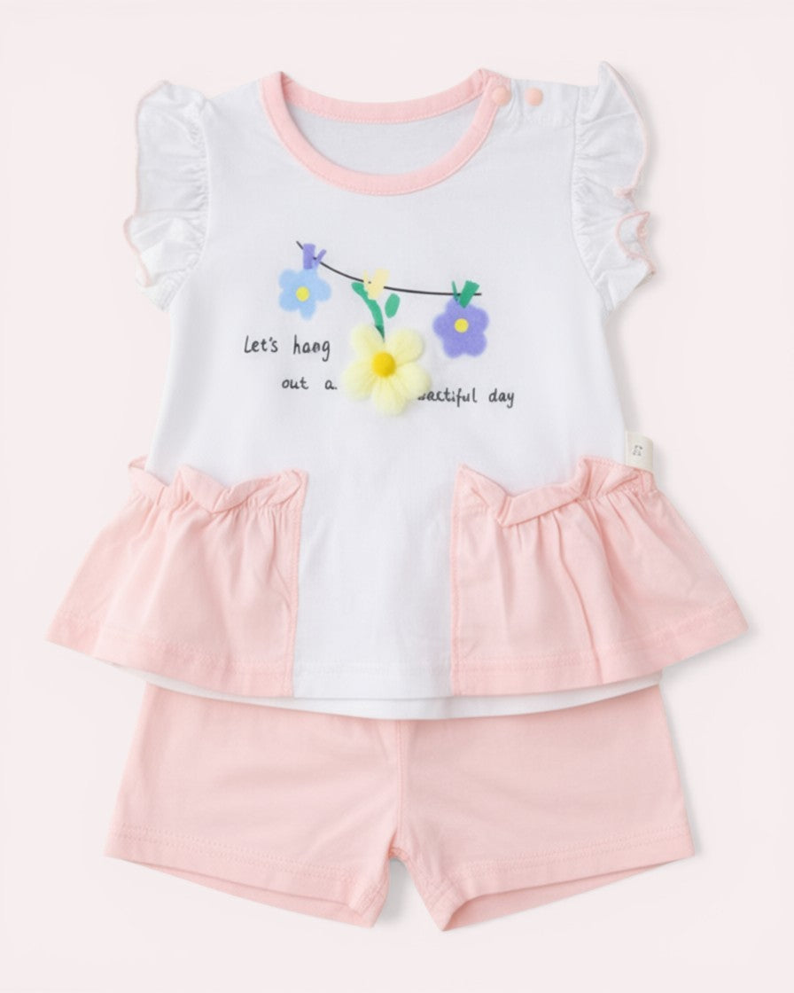Little Roots baby girl's soft pink floral top and shorts set. White top with ruffled sleeves and floral applique. Matching pink shorts.