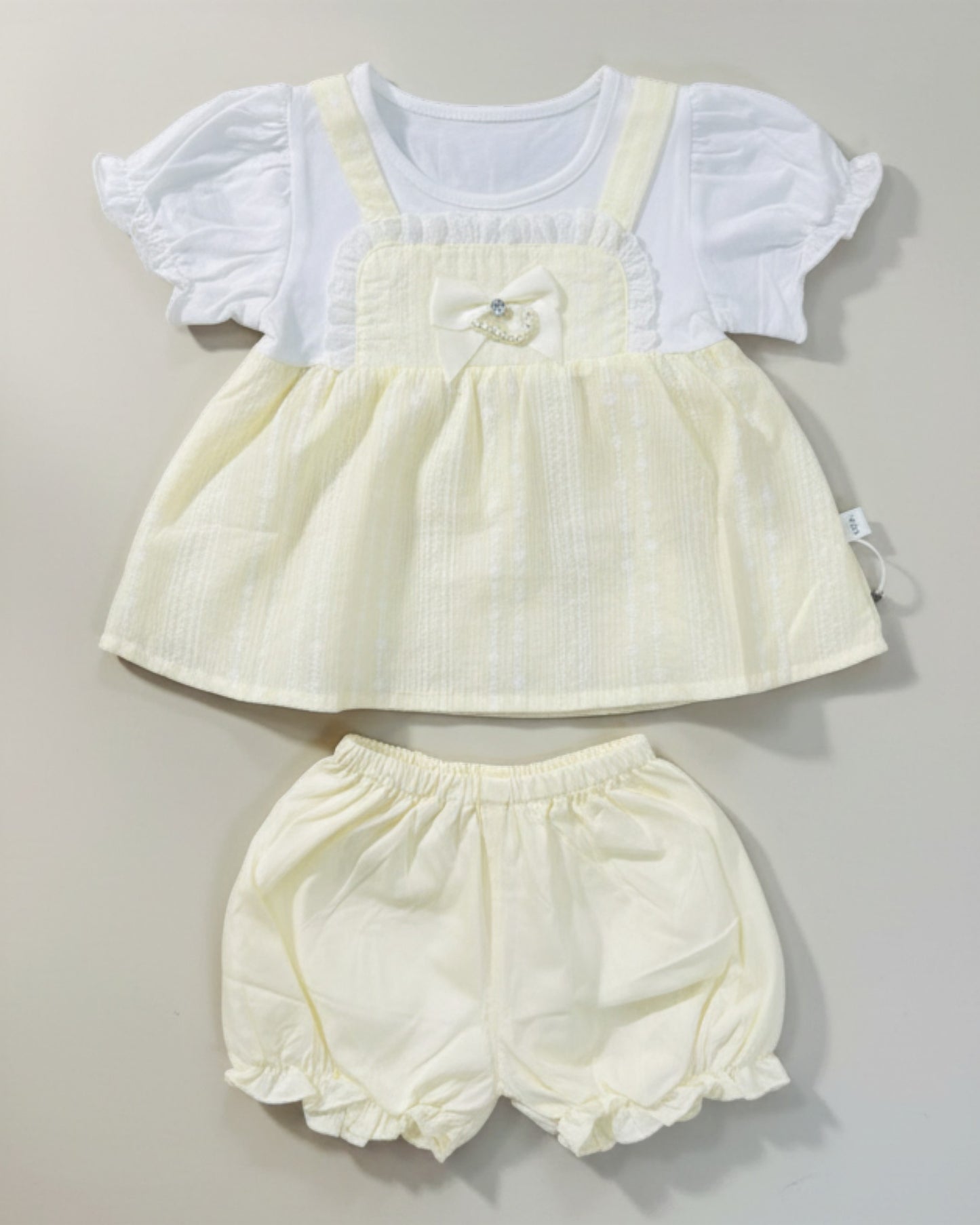 Little Roots baby girl's pale yellow cotton frock with white puff sleeves and matching shorts. Features a bow detail.