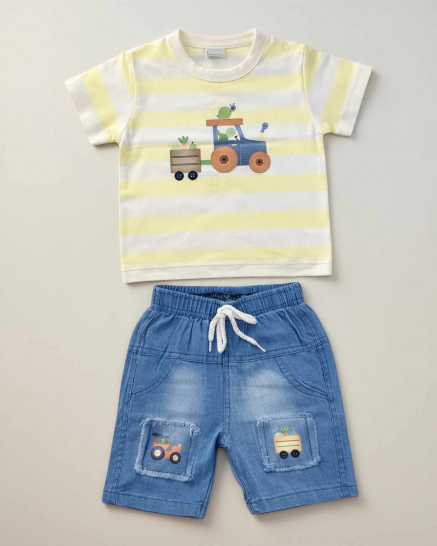 Little Roots Pakistan baby boy set: yellow and white striped T-shirt with tractor print, blue denim shorts with tractor patches. Cotton blend.