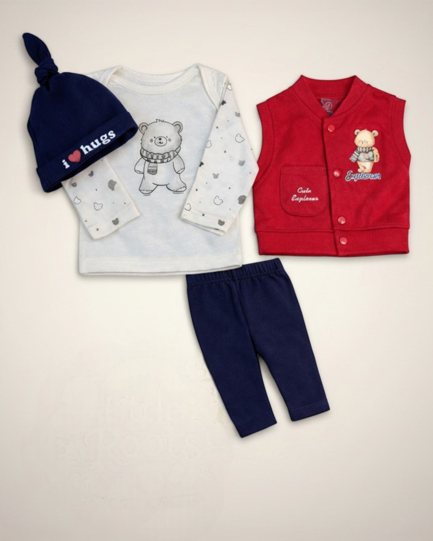 Little Roots newborn 4-piece set: navy knotted cap with 'I ❤️ Hugs', cream long-sleeve tee with bear print, red sleeveless vest, and navy trousers.