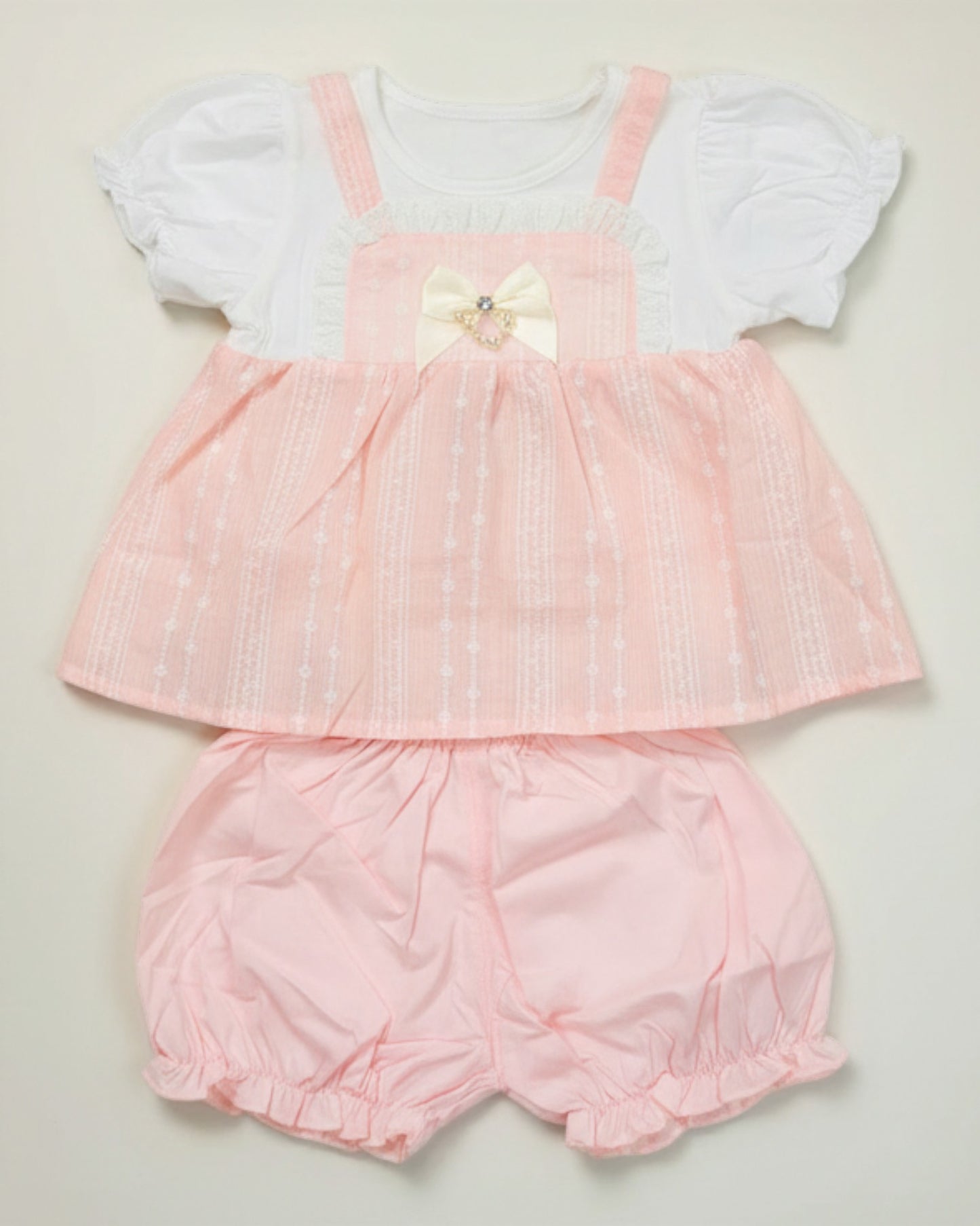 Little Roots baby girl peach textured frock with white puff sleeves and matching bloomers, featuring bow and pearl detail.