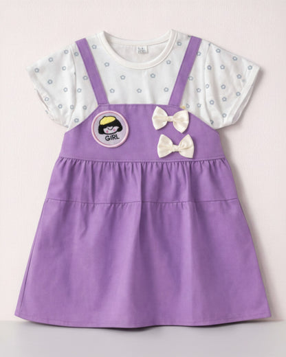 Little Roots baby girl purple pinafore dress with white floral print top, "Girl" patch, and double bow accents.