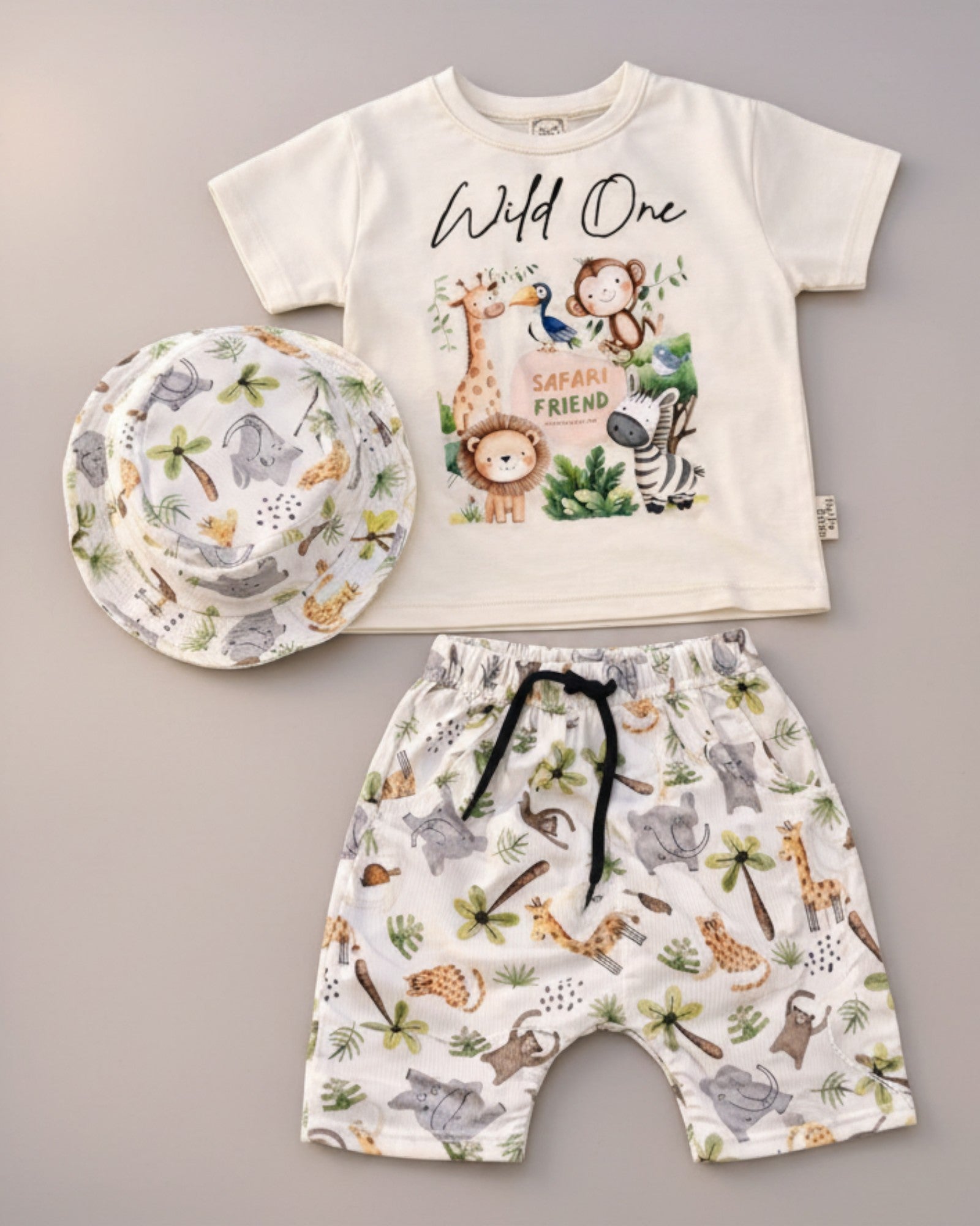 Little Roots Pakistan baby boy 3-piece safari jungle outfit: cream t-shirt with animal print, matching shorts, and bucket hat.